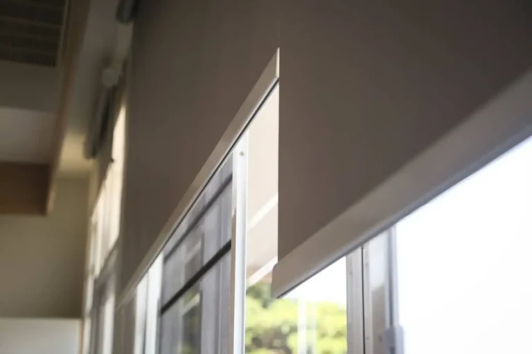 Close-up of two beige roller blinds with sunlight outside, quality window treatments in North Carolina.