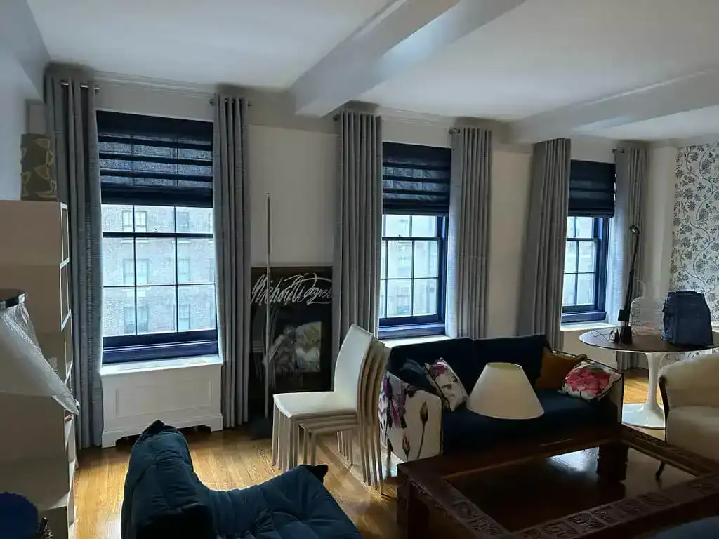 Living room with three windows, blue couches, patterned wallpaper, and North Carolina window treatments.