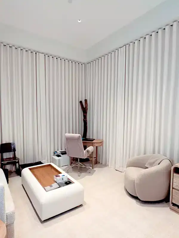 Modern office with cream chairs, ottoman, wood desk, and North Carolina style elegant window treatments.