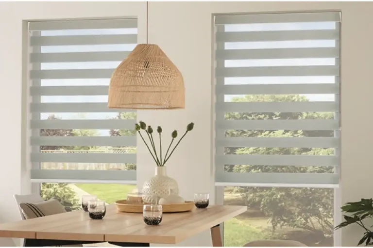 Dining area in North Carolina with a wooden table, zebra blinds, and a woven pendant light overhead.