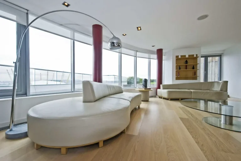 Modern living room in North Carolina with curved white sofas, wood floors, and striking red columns.