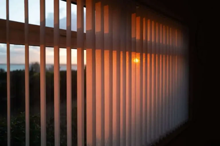 Sunset light streams through Window Treatments North Carolina, filling a dark room with warm orange hues.